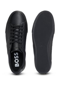 Zwarte leren sneakers met ronde neus, gestructureerde bovenkant, platte zwarte veters en een rubberen zool met een geperforeerd profiel. Logo op de binnenzool.
