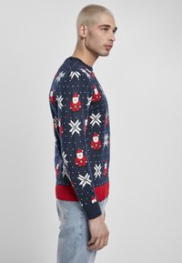 Pulover bleu marin cu modele de Moș Crăciun și fulgi de zăpadă, cu manșete și tiv roșu, fabricat din material tricotat.
