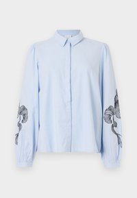 Camisa azul clara, com botões, de mangas longas e bufantes, apresentando padrões florais pretos bordados nas mangas exteriores. Material de algodão suave.