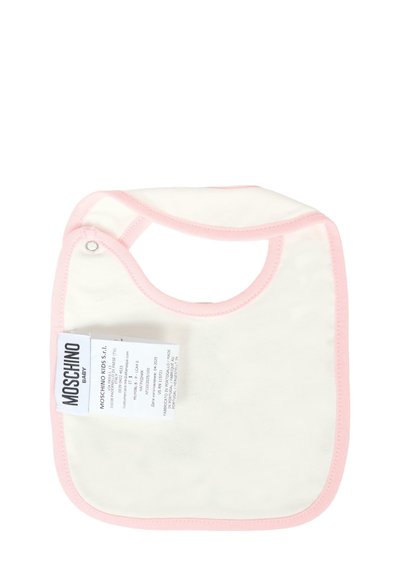 Bawełniany śliniak w kolorze kremowym z różowymi wykończeniami, o zaokrąglonym kształcie, z zapięciem na zatrzask. Zawiera metkę marki z informacjami o pielęgnacji i produkcie.