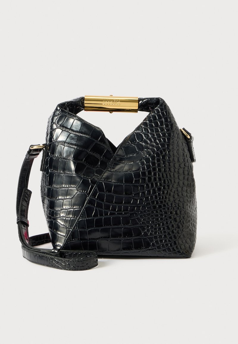 Sac à main noir en simili cuir crocodile avec une anse supérieure dorée, une bandoulière réglable et un design géométrique texturé.