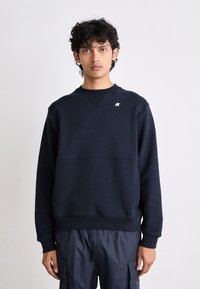 Felpa blu navale in misto cotone, con colletto a girocollo, polsini a costine e un piccolo logo sulla parte anteriore. Vestibilità classica e superficie testurizzata.