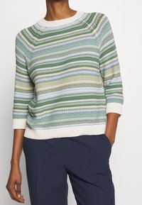 Gebreide trui met horizontale strepen in groen, blauw en geel. Heeft een ronde halslijn en geribde boorden, gemaakt van een gestructureerd materiaal.
