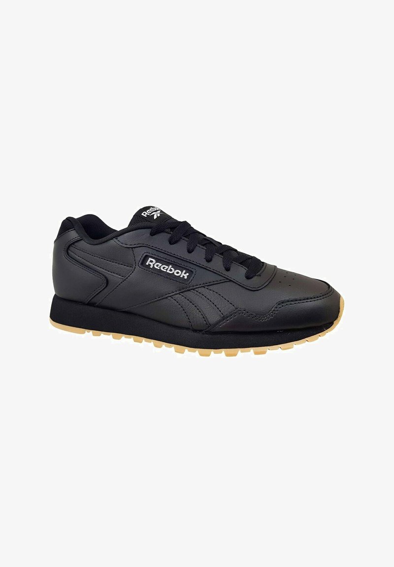 Baskets noires en cuir synthétique avec des coutures tonales, semelle en caoutchouc et un logo Reebok distinct sur le côté.