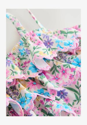 Blommig baddräkt med rosa, blå och gula blommor på en vit bakgrund. Har volangkanter och tunna justerbara axelband.