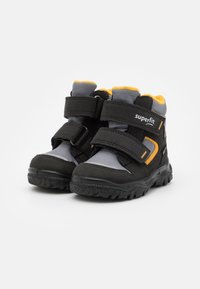 Scarpe nere e grigie con accenti arancioni, caratterizzate da un design alta, due cinghie in velcro e una suola in gomma testurizzata per una migliore trazione.