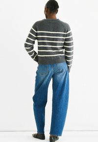 Gray striped sweater with a crew neck, paired with loose blue denim jeans. The outfit features a relaxed fit and a soft texture.