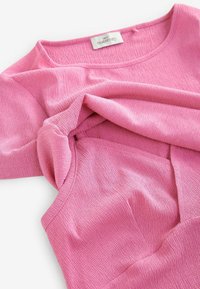 Roze zwangerschaps T-shirt met een geribde textuur en een ronde hals. De stof lijkt zacht en licht rekbaar, met zachte plooien bij de buste.