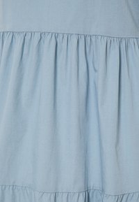 Hellblaues Baumwollkleid mit geraffter Taille. Es hat eine strukturierte Oberfläche und ein gestuftes Rockdesign.