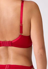 Czerwony biustonosz z regulowanymi satynowymi ramiączkami, złotymi ozdobami i gładką fakturą; posiada zapięcie na haftki z tyłu.