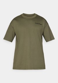 Olívovo zelené tričko s krátkym rukávom vyrobené z bavlny. Na prednej strane sa nachádza čierny nápis "PARÍŽ" a logo Nike. Design s okrúhlym výstrihom.