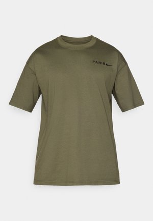 Olijfgroen t-shirt met korte mouwen van katoen. Voorzien van "PARIS" en een zwart Nike-logo op de voorkant. Met een ronde hals.