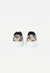 Sneaker beige con motivo e accenti neri, suola bianca in gomma e tomaia in tessuto testurizzato con design del logo.