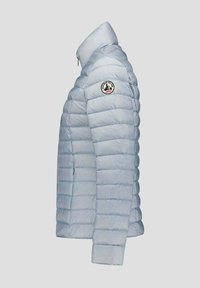Chaqueta acolchada azul claro con secciones acolchadas horizontales, cuello alto y parche redondo con logo en la parte superior de la manga izquierda. Cierre con cremallera.