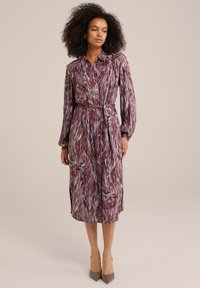 Abito camicia a maniche lunghe con un motivo astratto viola e blu, realizzato in tessuto leggero, con vita legata e fessure laterali.