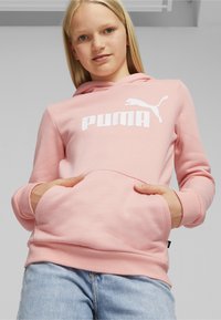Sudadera rosa con capucha, que presenta un gran logo blanco de "PUMA" y un pequeño gráfico de un gato saltando. Tiene un bolsillo delantero y puños acanalados.