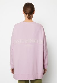 Sudadera de gran tamaño en suave algodón lavanda, con un corte relajado, puños acanalados y detalle en la parte posterior con el texto "SABOR de la NATURALEZA" en color crema.