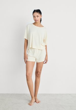 Lichtgeel loungewear-set met een relaxte T-shirt met korte mouwen en bijpassende shorts met een elastische tailleband. Zachte textuur.
