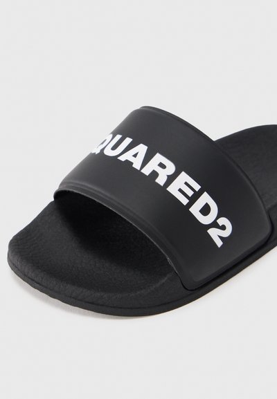 Sandală neagră cu talpă plată, având o curea lată cu text alb "SQUARED2". Talpă exterioară texturată, suprafață netedă a curelei și margini rotunjite.