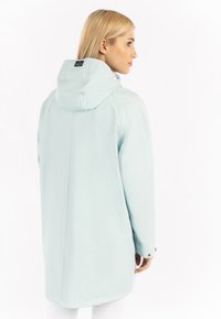 Világoskék vízálló dzseki kapucnival, sima textúrával, hosszú szabással és látható varrásokkal. Szabadtéri használatra alkalmas.