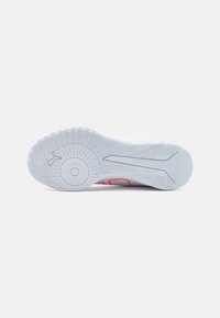 Suola di sneaker bianca con un motivo testurizzato, caratterizzata da una presa circolare centrale, accentuata da elementi di design arancioni e grigi.