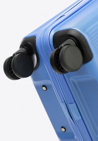 Hard-shell suitcase in light blue with a textured finish. Features dual black 360-degree wheels and a zippered closure.