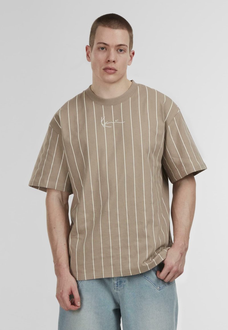 Brown striped t-shirt with short sleeves, featuring white vertical lines and a small logo on the chest. Fabric appears soft and casual.