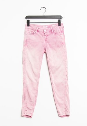 Jeans skinny in denim rosa con una finitura sbiadita, dotati di due tasche frontali, tasche posteriori e una zip. Appesi a una gruccia nera.