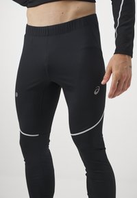 Leggings de sport noirs avec un design extensible et ajusté. Caractéristiques des accents réfléchissants et une texture lisse. Taille élastique pour le confort.