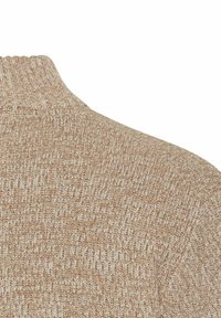 Beige geribbeld breiwerk met een hoge kraag, waarbij de textuur en de stiksels op het bovenste schoudergebied van een kledingstuk zichtbaar zijn.