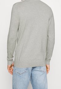 Grijze gebreide trui met lange mouwen, geribde manchetten en zoom, ontworpen met een ronde hals, zachte textuur en een ontspannen pasvorm.