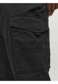 Zwarte cargobroek met een grote zijzak, gemaakt van duurzame stof met een zachte textuur en versterkte stiksels langs de naden.
