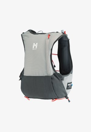 Homme en chemise orange et casquette portant un sac à dos gris avec des bâtons de trekking attachés, vu de dos.