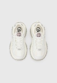 Bijele tenisice s teksturiranim mrežastim i kožnim gornjim dijelom, koje imaju jastučiće na jeziku, zaobljene vezice i kontrastne gumene đonove.