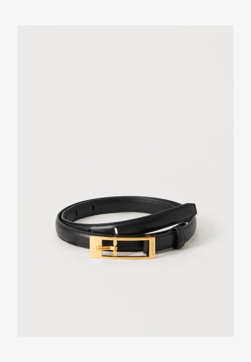 Ceinture en cuir noir roulée avec une boucle rectangulaire en métal doré sur un fond clair uni.
