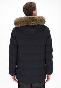 Marineblå dunjakke med pelsforet hætte, prydet med quiltet design, knapdekor på ærmerne og en glat tekstur.