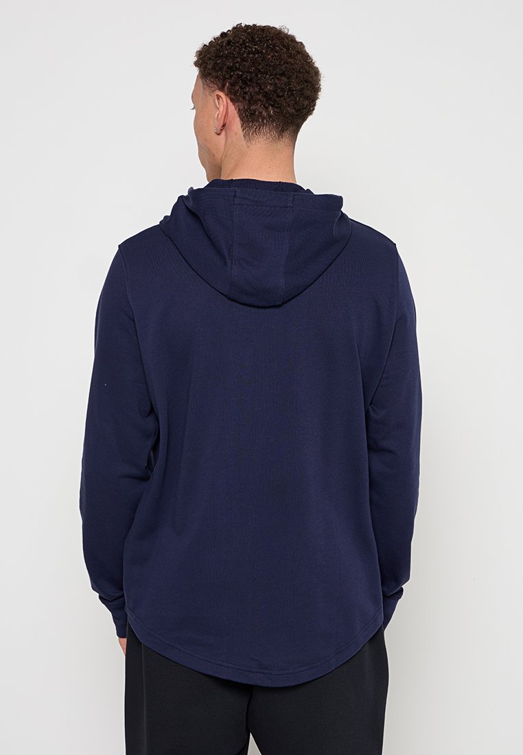 Sudadera azul marino de manga larga, con tejido texturizado y dobladillo curvado. Presenta una capucha espaciosa y un diseño minimalista sin marcas visibles.