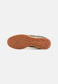 Semelle de chaussure avec une surface en caoutchouc texturé de couleur marron, ornée d'un motif de traction géométrique, conçue pour l'adhérence et la durabilité.
