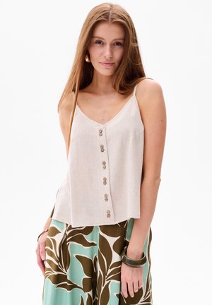 Lichtbeige linnen top met V-hals, voorzien van een knoopsluiting aan de voorkant en dunne bandjes. Gekleed met gestreepte groene en bruine broek.