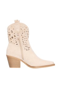 Beige suède enkellaars met geperforeerde bloemenpatronen, zijrits, aantreklus, puntige neus en gestapelde houten blokhak.