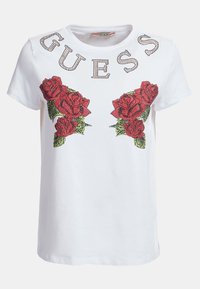 Weißes Baumwoll-T-Shirt mit kurzen Ärmeln, das rote Rosenmuster und grüne Blätter zeigt. "GUESS" ist in Strasssteinen über den Blumen geschrieben.