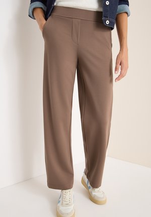 Pantalones de pierna ancha marrones hechos de una tela suave con una textura lisa, con bolsillos laterales y una cinturilla plana, combinados con zapatillas blancas.