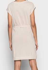 Robe beige à rayures avec de courtes manches roulées, taille élastique et ceinture nouée, fabriquée à partir d'un tissu doux et texturé.