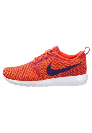 Chaussure de course tricotée orange et violette avec une semelle blanche et le logo Nike swoosh sur le côté, vue de l'extérieur.