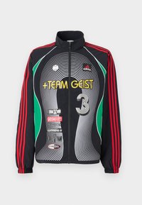 Svart zip-up Adidas treningjakke med røde striper på ermene, grønne detaljer, hvite buede linjer og gule "TEAM GEIST"-bokstaver på fronten.