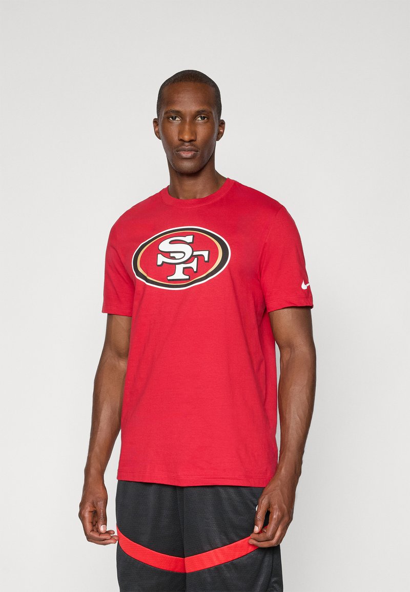 Red cotton t-shirt featuring a central black and white San Francisco logo, short sleeves, and a crew neckline. Paired with black shorts.