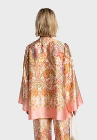 Veste style kimono en soie avec un motif cachemire vibrant en rose, orange et or. Caractérisée par des manches larges et un ourlet à la brillance lisse.
