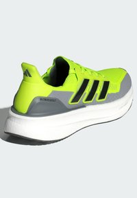 Neon žute atletske tenisice s crnim prugama, sivi detalji, udoban bijeli potplat i teksturirani gornji materijal za prozračnost.