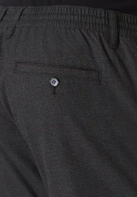 Grau karierte Hose mit feiner Textur, ausgestattet mit einem elastischen Bund, Seitentasche und einer geknöpften Gesäßtasche.