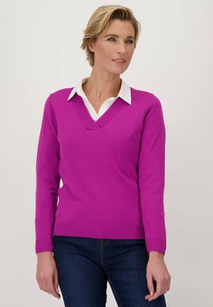 Polo met V-hals en lange mouwen in felroze, gemaakt van zacht gebreid materiaal. Bevat geribbelde manchetten en zoom. Draagt over een witte coll shirt.